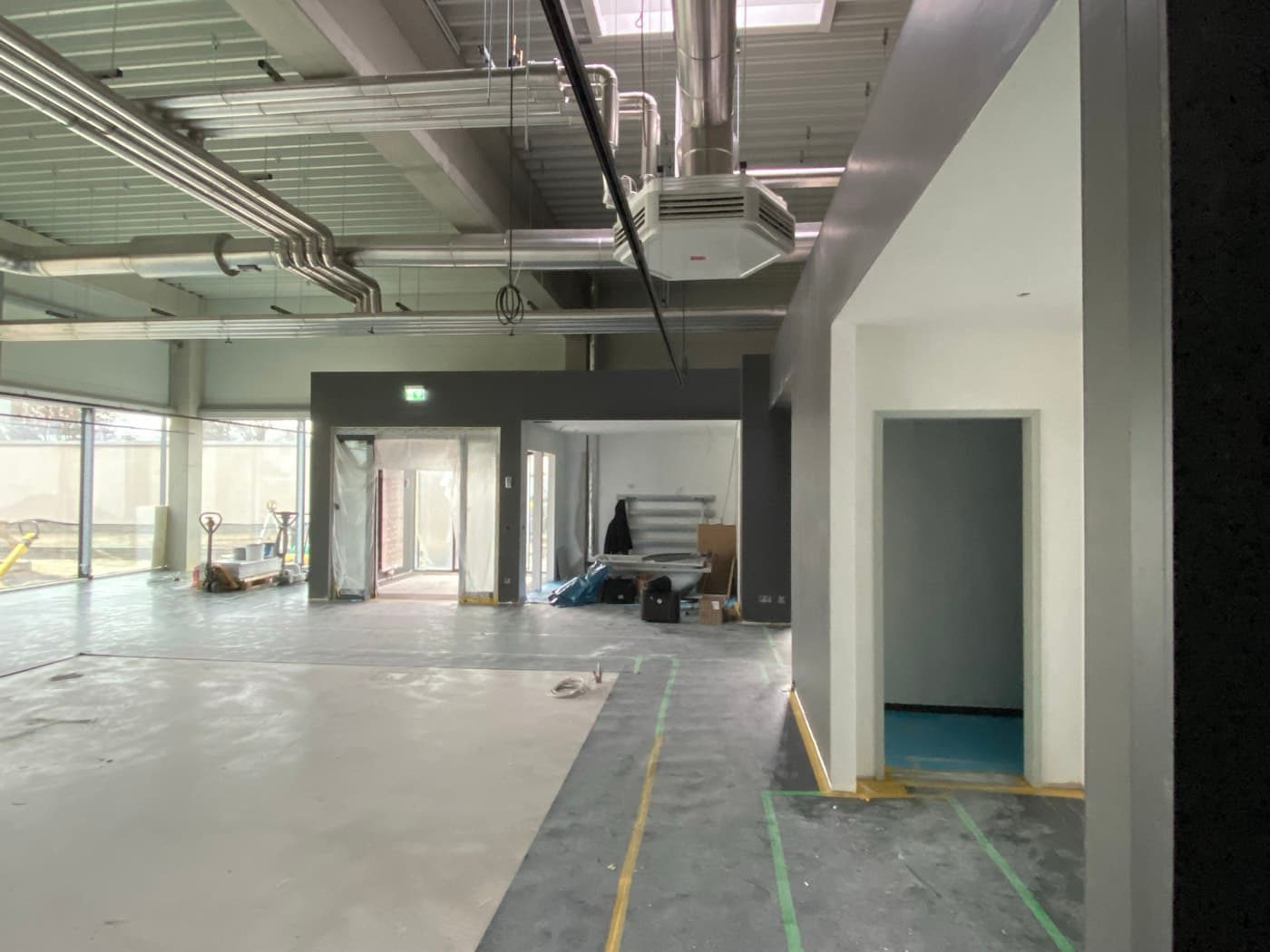 Sichtbar verlegte Lüftungskanäle und ein Deckenumluftgerät in einem Gebäude im Innenausbau