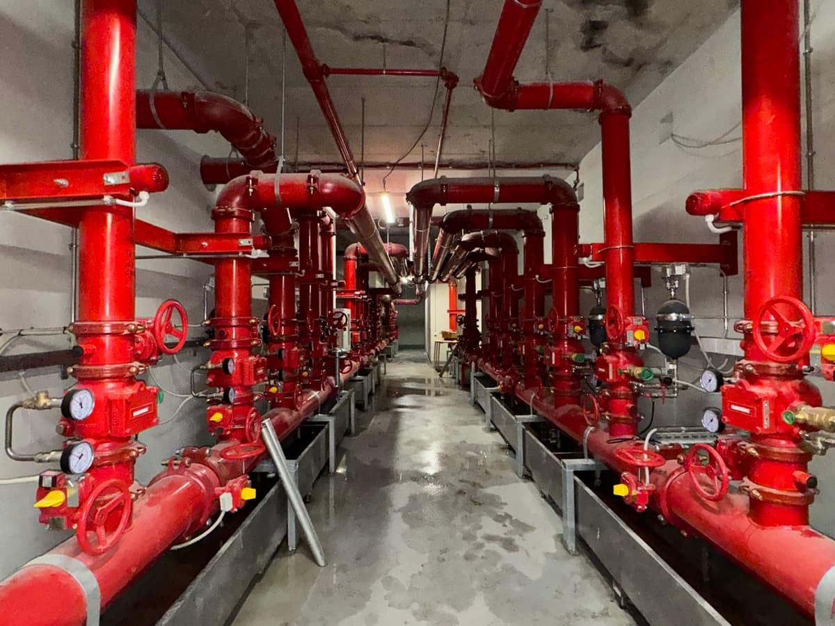 Sprinklerzentrale mit rot lackierten Steigleitungen, Ventilstationen und Manometern im Untergeschoss